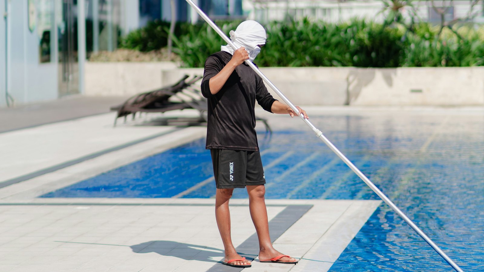 A pool technician skimming the surface of a clear pool
